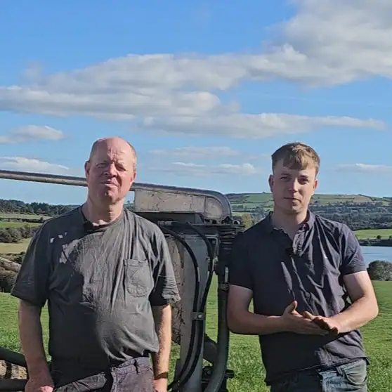 James and Steven Downey standing outdoors with scenic landscape background.