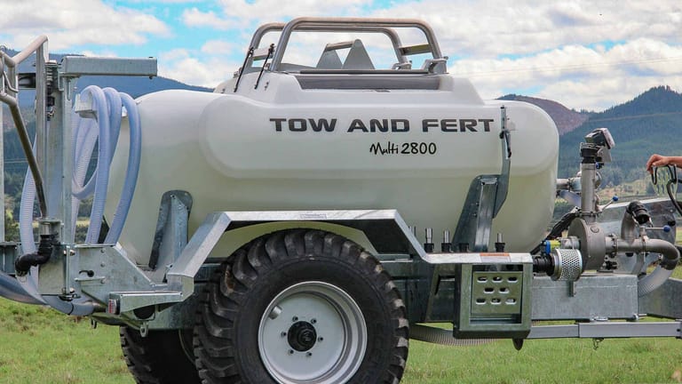 Close-up side view of a Tow and Fert Multi 2800 sprayer, showing its white tank, branding and large wheel.