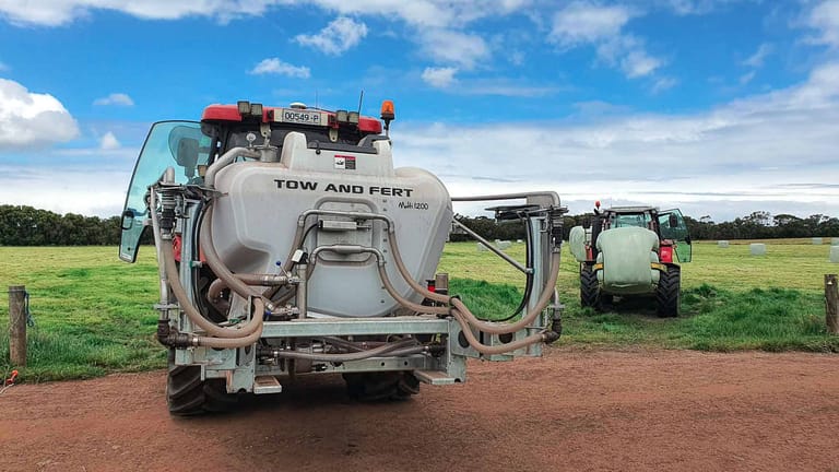 Close-up rear view of a Tow and Fert Multi 1200 sprayer, showing its tank, hoses and spray system on a farm.
